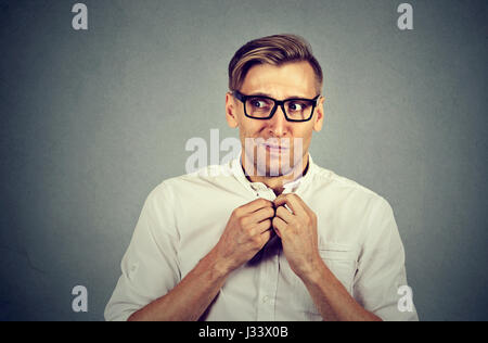 Sottolineato nervoso giovane allievo ritiene scomodo guardando lontano sideway ansiosamente craving qualcosa di isolato muro grigio Sfondo. Emozioni umane faccia ex Foto Stock