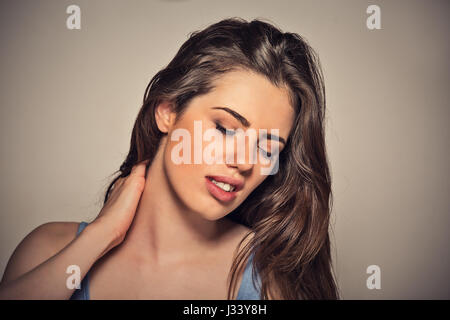 Indietro e la spina dorsale della malattia. Closeup ritratto stanco donna massaggiare la sua dolorosa collo isolato sul muro grigio Sfondo. Volto umano espressione. Fatig cronica Foto Stock