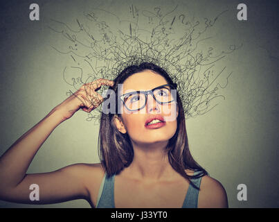 Closeup ritratto giovane donna di graffiare la testa, pensando fantasticando con fusione del cervello in linee interrogativi guardando in alto isolato su sfondo grigio Foto Stock