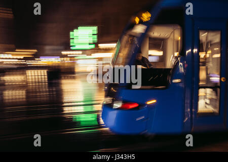 Sfocato il tram che si muove attraverso un umide e piovose del centro della città di Cracovia, in Polonia. I mezzi di trasporto pubblici motion blur applicato nella fotocamera. Foto Stock