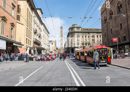 La gente a piedi in via Rizzoli con una vista delle due antiche torri in background in Bologna Foto Stock