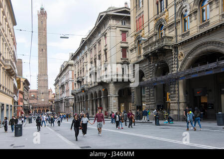 La gente a piedi in via Rizzoli con una vista delle due antiche torri in background in Bologna Foto Stock