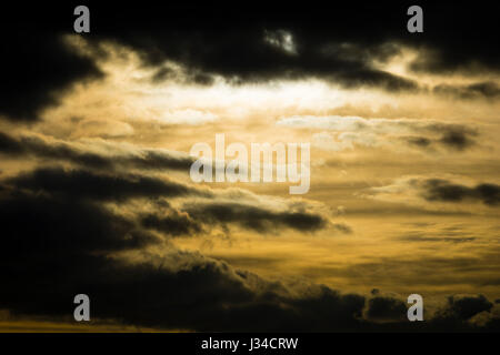 Drammatica nuvole nel cielo con luce arancione dal sole a picco attraverso. Foto Stock