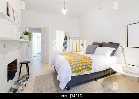 Moderno ed elegante camera da letto con bagno privato e arredamento giallo accenti Foto Stock