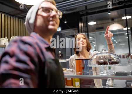 Donna felice che mostra qualcosa al barista presso il cafe Foto Stock