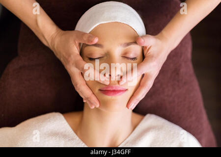 Donna con massaggio viso e testa a spa Foto Stock