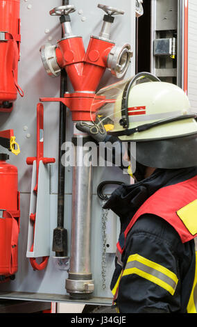 Firefighter lavora sul motore Fire Foto Stock