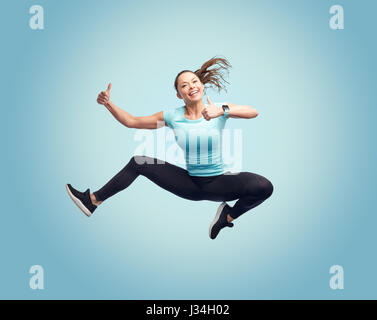 Sorridenti sportivo da donna giovane salti in aria Foto Stock