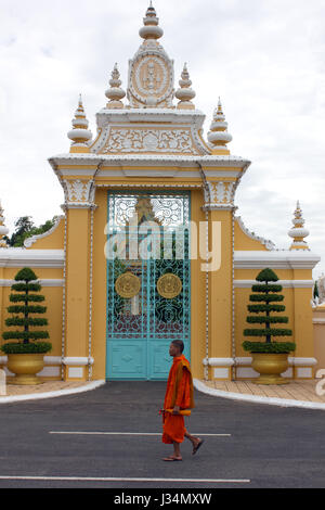 Un monaco buddista passeggiate passato un cancello ornati di Palazzo Reale, Phnom Penh Cambogia. Foto Stock