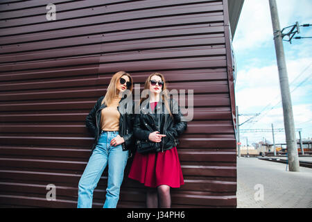 Conversazione tra due donne nella città.Outdoor Lifestyle ritratto di due migliori amici hipster ragazze indossano Elegante giacca di pelle e occhiali da sole, going crazy e avente un grande tempo insieme Foto Stock