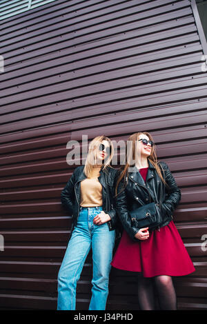 Conversazione tra due donne nella città.Outdoor Lifestyle ritratto di due migliori amici hipster ragazze indossano Elegante giacca di pelle e occhiali da sole, going crazy e avente un grande tempo insieme Foto Stock