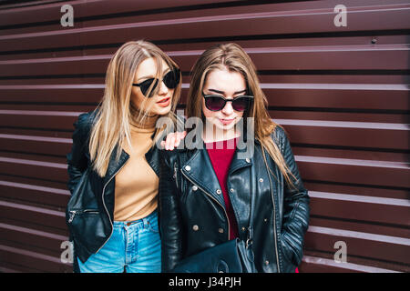 Conversazione tra due donne nella città.Outdoor Lifestyle ritratto di due migliori amici hipster ragazze indossano Elegante giacca di pelle e occhiali da sole, going crazy e avente un grande tempo insieme Foto Stock