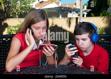 Modello rilasciato immagine del giovane ragazza caucasica e ragazzo, bambini con tecnologia telefono sistema di gioco musica social media Foto Stock