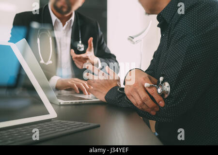 Medical co il concetto di lavoro,medico lavora con tavoletta digitale e computer laptop formeeting il suo team in ufficio moderno all'ospedale Foto Stock