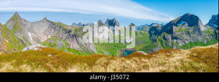 Foto panoramica di scogliere, montagne di origine glaciale e gli ingressi da una cresta acuta nelle Isole Lofoten con cielo blu e ventresche cloud che li copre. Foto Stock