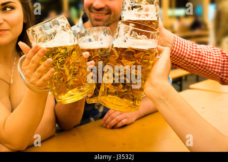Le ragazze in tradizionale Dirndl vestiti sono bere birra e divertirsi con i loro amici al Oktoberfest a Monaco di Baviera Foto Stock