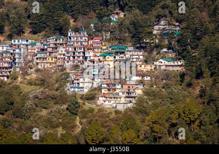 Tipiche case di montagna e gli edifici su ripidi fittamente boscosa collina himalayana piste, McLeodGanj, Dharamshala, Himachal Pradesh, India del nord Foto Stock