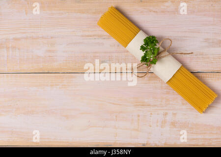 Asciugare gli spaghetti legato con la corda sul legno scuro tabella Foto Stock