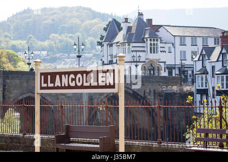Llangollen stazione ferroviaria firmare con la città in background e il ponte che attraversa il fiume Dee in Llangollen, Denbighshire Foto Stock