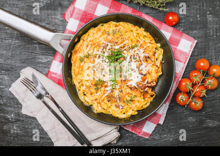 Pasta casseruola con uova, pomodori secchi e formaggio in padella su sfondo nero, vista dall'alto Foto Stock