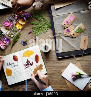 Le mani la scrittura di dettaglio di fiori secchi di raccolta in Notebook lavori fatti a mano Hobby Foto Stock