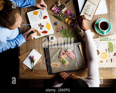 Le mani la scrittura di dettaglio di fiori secchi di raccolta in Notebook lavori fatti a mano Hobby Foto Stock