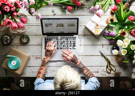 Donna con notebook cercando su Internet Negozio di Fiori Piante Online Foto Stock