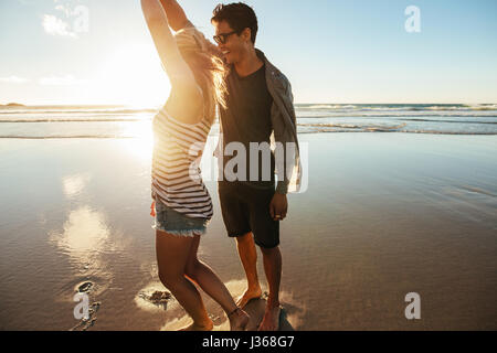 Colpo di amare giovane coppia danzante sulla spiaggia un giorno d'estate. Giovane uomo e donna ballare in riva al mare. Foto Stock