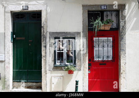 Sportelli anteriori di due case adiacenti, i numeri 164 e 166, uno rosso, uno verde con una piccola finestra tra loro con due scarponi che agiscono come le piantatrici. Foto Stock