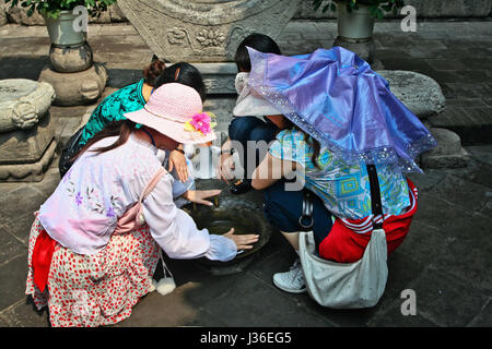 Donna turistici cinesi cercano di rendere il suono da pentola in ferro in Pingyao,central nella provincia dello Shanxi in Cina. Foto Stock