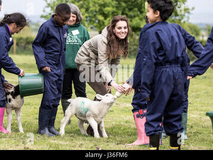 La Duchessa di Cambridge alimenta Stinky l'agnello in un campo con la scuola i bambini durante una visita alle aziende agricole per bambini di città della carità in Gloucester, dove lei ha visto il loro lavoro dando ai giovani dalla città dell'interno la possibilità di trascorrere una settimana in una fattoria di lavoro. Foto Stock