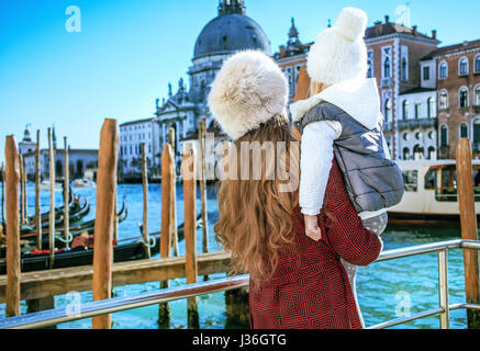 Un altro mondo vacanza. Visto da dietro il moderno madre e figlia di viaggiatori sul terrapieno in Venezia, Italia in inverno avendo escursione Foto Stock