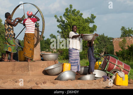 Il Burkina Faso, Gaoua , donne di recuperare acqua potabile dalla pompa acqua con ruota che gira nel villaggio / Burkina Faso Gaoua, Frauen holen Wasser von einem Brunnen mit Drehpumpe Foto Stock