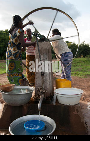 Il Burkina Faso, Gaoua , donne di recuperare acqua potabile dalla pompa acqua con ruota che gira nel villaggio / Burkina Faso Gaoua, Frauen holen Wasser von einem Brunnen mit Drehpumpe Foto Stock