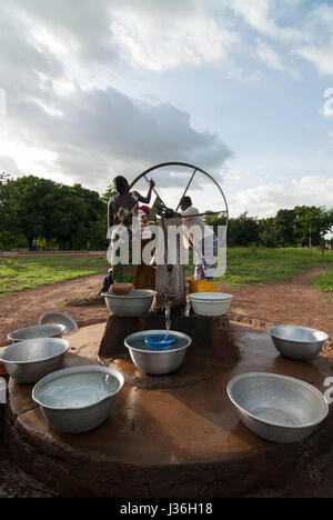 Il Burkina Faso, Gaoua , donne di recuperare acqua potabile dalla pompa acqua con ruota che gira nel villaggio / Burkina Faso Gaoua, Frauen holen Wasser von einem Brunnen mit Drehpumpe Foto Stock