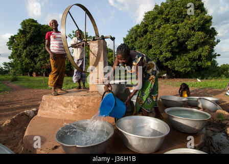 Il Burkina Faso, Gaoua , donne di recuperare acqua potabile dalla pompa acqua con ruota che gira nel villaggio / Burkina Faso Gaoua, Frauen holen Wasser von einem Brunnen mit Drehpumpe Foto Stock