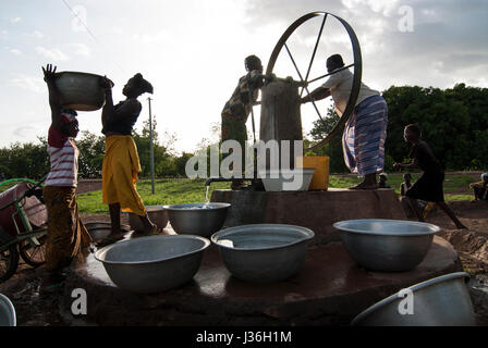 Il Burkina Faso, Gaoua , donne di recuperare acqua potabile dalla pompa acqua con ruota che gira nel villaggio / Burkina Faso Gaoua, Frauen holen Wasser von einem Brunnen mit Drehpumpe Foto Stock