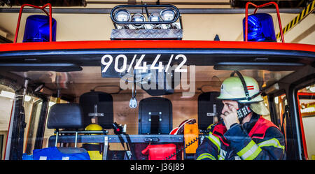 Vigile del fuoco in un camion dei pompieri in azione con walkie talkie - HDR Foto Stock