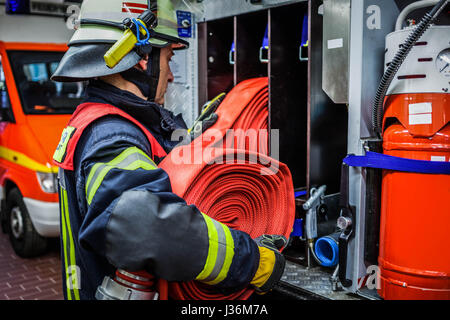 Vigile del fuoco nella stazione dei vigili del fuoco con un tubo flessibile di acqua in mano - HDR