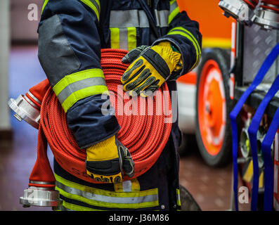 Vigile del fuoco nella stazione dei vigili del fuoco con un tubo flessibile di acqua in mano - HDR Foto Stock