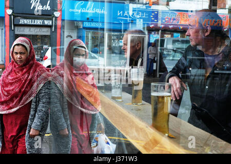 Una donna asiatica passando un pub dopo la finestra di shopping in Cardiff Wales UK Foto Stock