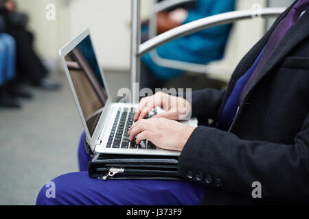 Imprenditore lavora con il computer portatile in metropolitana Foto Stock