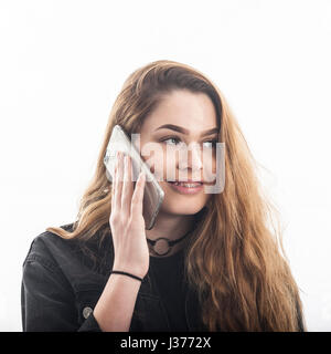 Un grazioso 15 anno vecchia ragazza parlando sullo smartphone cercando felice in studio contro uno sfondo bianco nel Regno Unito Foto Stock