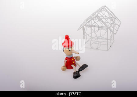 Pinocchio è seduto accanto a un modello di casa Foto Stock