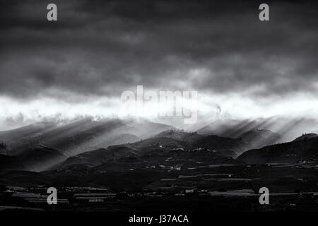 Raggi di sole risplendere nuvole temporalesche all'alba sopra le colline e le montagne a Guia de Isora sulla zona ovest di Tenerife, Isole Canarie, Spagna Foto Stock