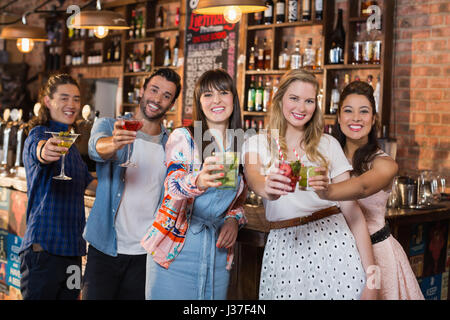 Ritratto di amici sorridenti tenendo le bevande al bar Foto Stock