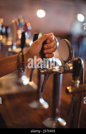 Close-up di barman mani con rubinetto di birra in pub Foto Stock