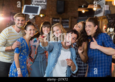 Allegro amici prendendo selfie attraverso il telefono cellulare in pub Foto Stock