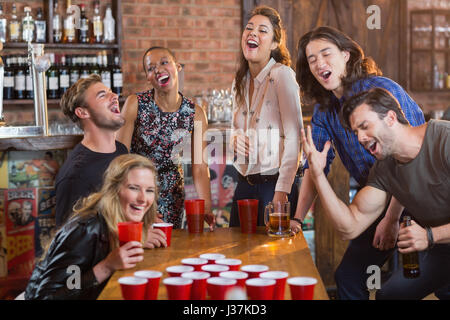 Amici a giocare Pong della birra sul tavolo in bar Foto Stock