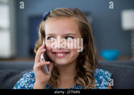 Felice ragazza parlando al telefono mobile nel salotto di casa Foto Stock